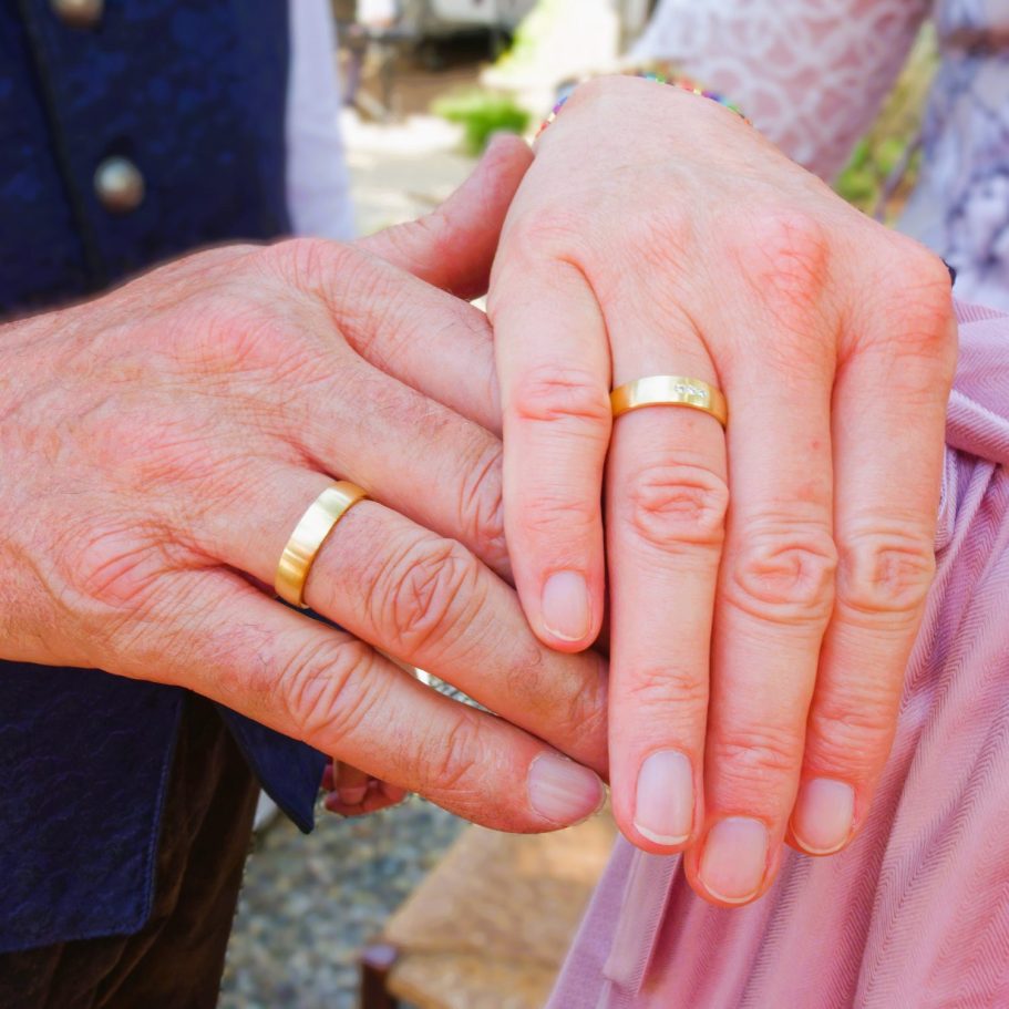 Hände mit Eheringen, die zusammengelegt sind, symbolisieren eine Verbindung oder Ehe.